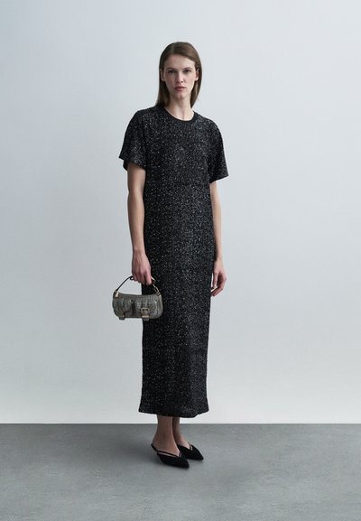 Μαύρο, λαμπερό μάξι φόρεμα με κοντά μανίκια, σε συνδυασμό με μια υφασμάτινη γκρι τσάντα και μαύρα μυτερά μπαλαρίνια. Απλός, λιτός σχεδιασμός.