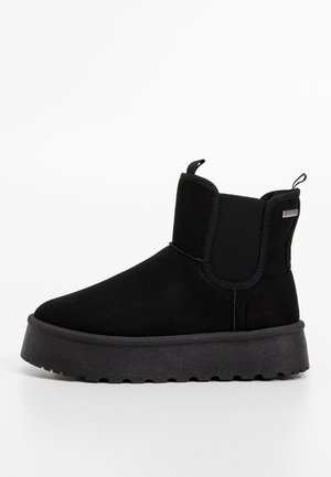 Bottine à plateforme noire avec panneaux latéraux élastiques et languettes sur fond blanc.