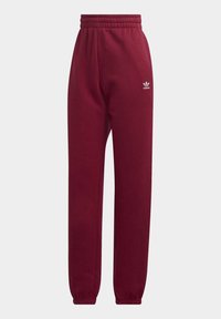 Pantalon de survêtement bordeaux en tissu doux avec une taille et des poignets élastiques. Présente un petit logo Adidas blanc sur la cuisse gauche.