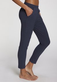 Navy ribbed pants with a fitted design, featuring side pockets and a tapered leg that ends just above the ankle. Soft texture and elastic waistband.