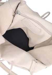 Borsa in suede beige con una singola tasca con zip e una fodera nera testurizzata. Presenta bordi morbidi e spallacci sottili per il trasporto.
