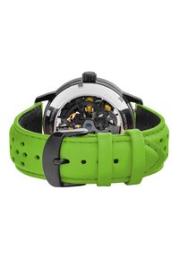 Reloj con correa de cuero perforado verde que presenta una caja de acero inoxidable negro, parte trasera transparente y movimiento mecánico visible.