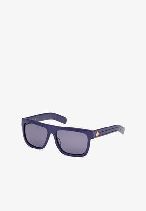 Gafas de sol de plástico morado con lentes rectangulares. Lentes ahumados de color gris oscuro y acentos de tres rayas en las patillas, que presentan un logo dorado.