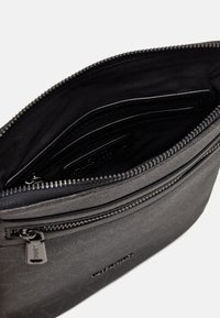 Black zippered bag with a structured design, featuring a smooth exterior, interior slip pockets, and a small metal zipper pull.