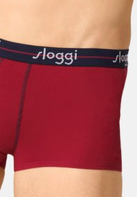 Punaiset puuvillaiset bokserishortsit, joissa on laivastonsininen joustava vyötärönauha, jossa on "sloggi"-logo. Sileä pinta, keskikorkea vyötärö ja kontrastiva tikkaukset.