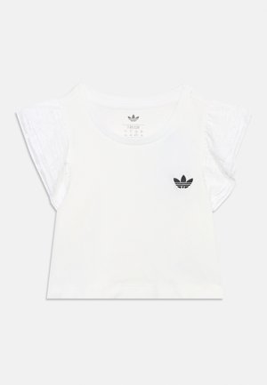 Bílé krátké tričko s krajkovými rozevlátými rukávy a malým černým logem Adidas na levé straně hrudi pro děti ve velikosti 7-8 let.