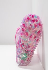 Semelle de sneaker translucide rose avec un motif de points colorés, dotée d'une adhérence texturée et d'un design de semelle géométrique pour une traction optimale.