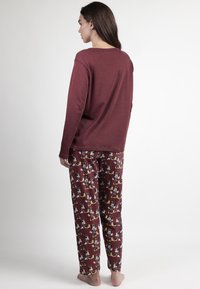 Top burdeos de manga larga con escote redondo, combinado con pantalones de pijama con patrones que presentan diseños divertidos y colores vibrantes.