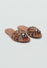 Brown leather sandals with a woven strap design, flat sole, and tan footbed. Features contrasting stitching along the edges.