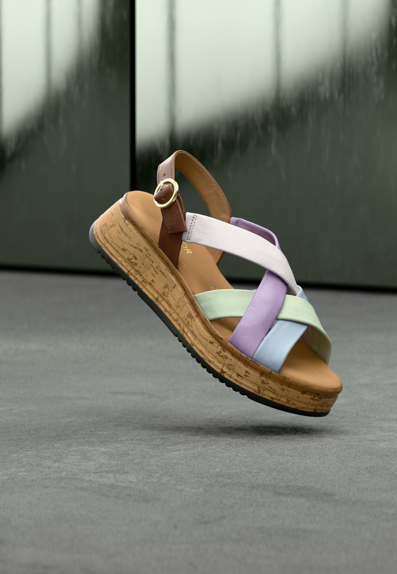 Πολύχρωμο τρίγωνο σανδάλι με λουριά που διασταυρώνονται, με λωρίδες σε μωβ, ανοιχτό μπλε και πράσινο. Μεσόσολα από φελλό και καφέ λουρί αστραγάλου με αγκράφα.