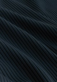 Mörkt ribbat tyg med en texturerad yta, med jämnt fördelade vertikala ränder. Materialet verkar slätt och mjukt.