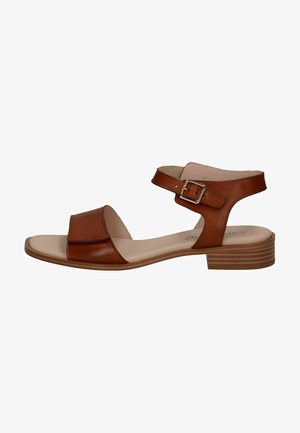 Sandal de cuero marrón con una correa ancha y cierre de hebilla en el tobillo, tacón plano y un forro interior ligero. Superficie lisa con un diseño minimalista.