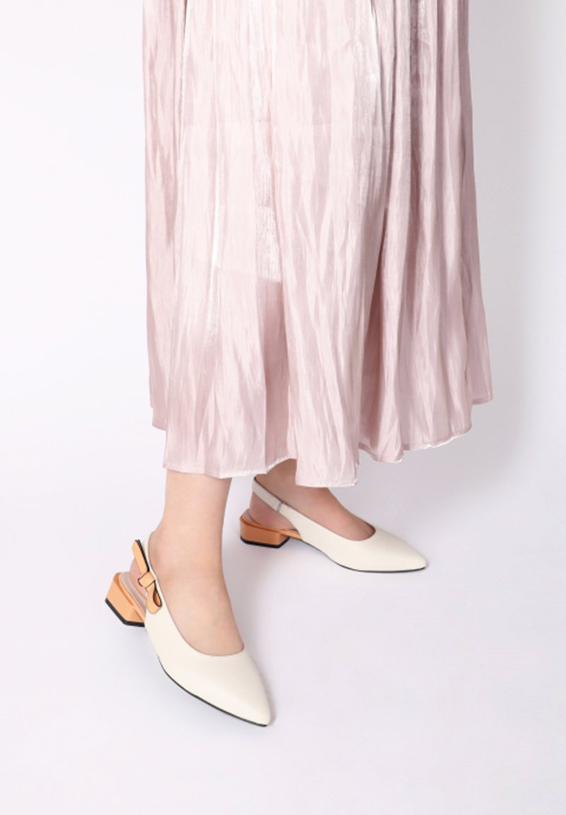 Hvide slingback sko med spids tå, med en tekstureret sål og en orange detalje på den lave blokhæl.