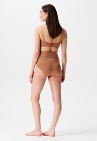Bruine beha met verstelbare bandjes en bijpassende hoogzittende slips, gemaakt van soepele stof, heeft een naadloos ontwerp en een minimalistische stijl.