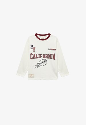 Pitkähihaisen valkoisen t-paidan marooniväriset yksityiskohdat, jossa on graafinen teksti "CALIFORNIA" ja jalkapallokuva. Puuvillakankainen, rento malli.