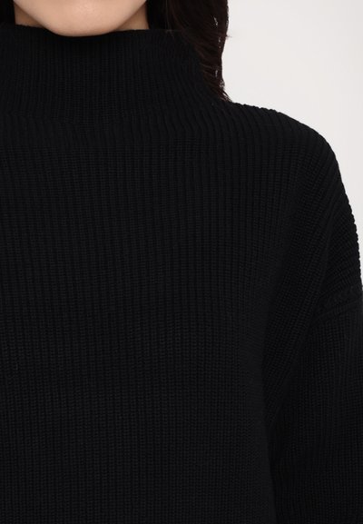 Black ribbed turtleneck sweater featuring a textured knit design with a high collar. The material appears soft and thick for warmth.