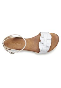 White leather sandal with a ruffled strap, open toe, and a light brown, textured sole. Ankle strap with a metal buckle detail.