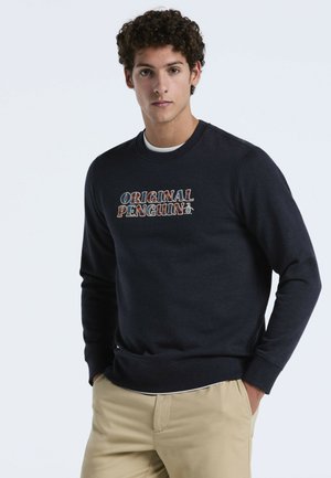 Sweatshirt bleu marine à col rond en tissu doux, avec un logo brodé multicolore "Original Penguin" sur le devant.