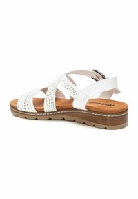 Sandal bianco con tomaia perforata, cinturino regolabile alla caviglia e soletta imbottita color tan, posata su una suola marrone texturizzata.