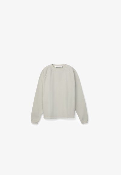 Sudadera gris claro de manga larga con cuello redondo, puños de canalé y un sutil logo de la marca en el pecho, presentada sobre un fondo blanco.