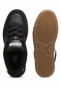 Baskets de sport noires avec une tige en cuir et textile, comportant un logo Puma blanc sur la languette et une semelle extérieure en caoutchouc gomme texturée.