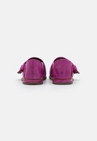 Mocassins en cuir fuchsia avec une texture douce, semelles plates et accents de glands sur les côtés, présentant des dos arrondis et des détails de coutures minimales.