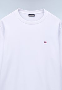 Tricou alb cu mâneci lungi din bumbac, cu guler rotund și un mic steag norvegian brodat în roșu și albastru pe piept.