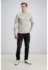 Pleteni pulover v krem barvi s črno/sivimi črtami, okrogel izrez, teksturiran vzorec. Kombiniran s črnimi jeans hlačami in belimi supergami.