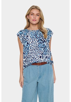 Blå och vit leopardmönstrad blus med korta ärmar, draperad design och rund halsringning. Matchad med högmidjade ljusblå jeans.