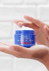 Kiehl's Ultra Facial Oil-Free Gel Cream i en blå burk, med en vit krämig konsistens, hållen i en hand mot en ljus bakgrund.