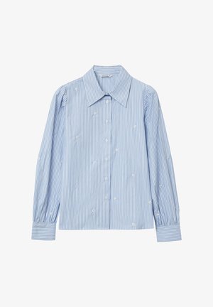 Camicia a righe blu chiaro con colletto classico, maniche lunghe a sbuffo e chiusura con bottoni; presenta un delicato ricamo floreale su tutta la superficie.