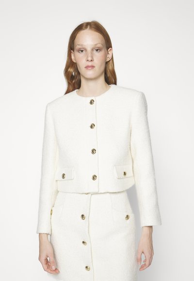 Λευκό σακάκι από tweed με κοντό σχέδιο, στρογγυλή λαιμόκοψη και μακριά μανίκια. Διαθέτει χρυσά κυκλικά κουμπιά και μπροστινές τσέπες.