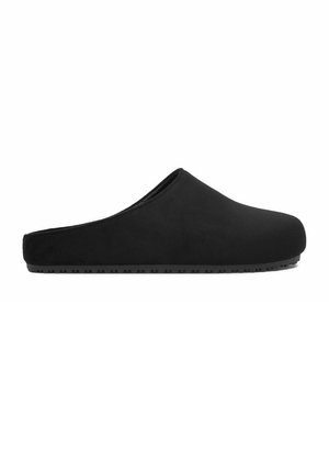 Zapatilla negra de tipo slip-on con puntera cerrada y redondeada, talón bajo y suela de goma texturizada para uso en interiores.