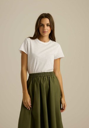 Biała bawełniana koszulka z krótkim rękawem, zestawiona z długą, oliwkową spódnicą plisowaną z elastyczną talią.