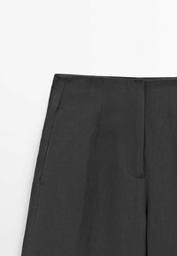 Pantalons gris foncé avec une texture lisse, présentant un devant plat, des poches latérales et une coupe droite. Coupe ajustée sans hardware visible.