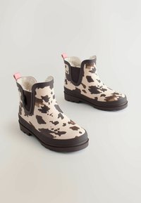 Sorte gummistøvler med cow-print og en brun sål, blødt inderskud og pink trækflapper. Har elastiske sidepaneler for nem påtagning.