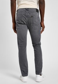Gray denim jeans with a slim fit, visible back pockets, and a black "Lee" label on the waistband. Smooth texture with minimal fading.