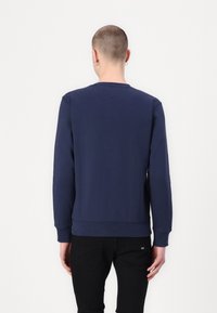 Sudadera azul marino con mangas largas, cuello redondo y puños acanalados. Tejido liso, diseño sencillo y sin logotipos ni patrones visibles.