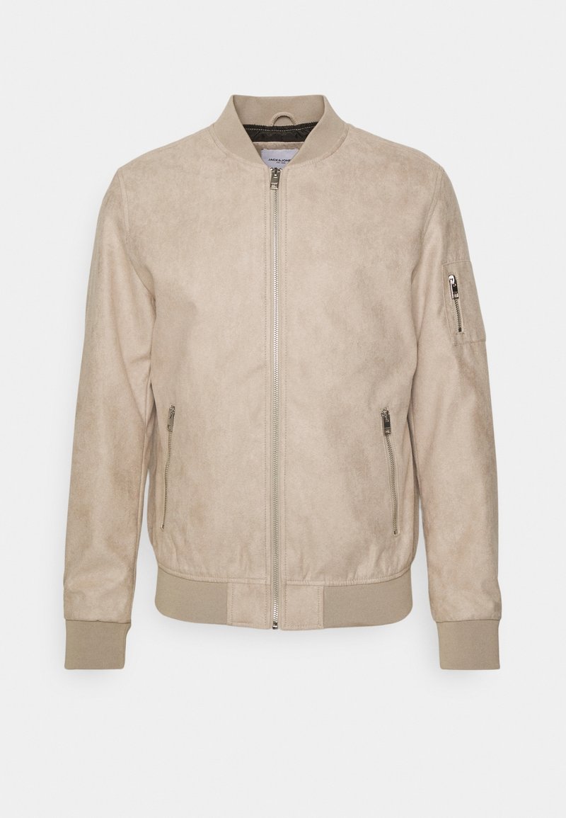 Chaqueta bomber beige hecha de suave material de ante, con cierre delantero, puños acanalados y un bolsillo con cremallera en el brazo izquierdo. Textura suave.