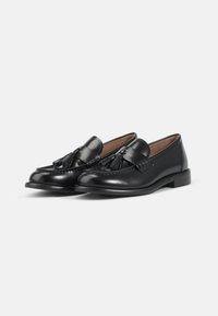Svarta läderloafers med en tofsdekoration, rund tå och låg klack. Slät textur med kontrasterande sömmar.