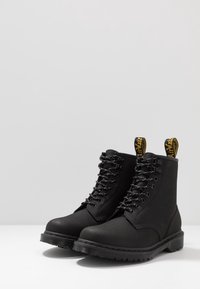 Zwarte enkellaarsjes gemaakt van duurzaam materiaal, met een veterontwerp, ronde neus en een geel merkteken aan de achterkant. Gestructureerde zool voor grip.