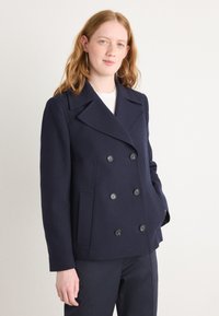 Manteau de marin en mélange de laine, avec un design croisé, de grands boutons noirs et des poches latérales. Texture lisse.