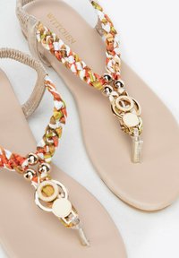 Platte sandalen met gevlochten textiele banden in oranje, groen en wit, met gouden hardware-accenten en een beige zool.