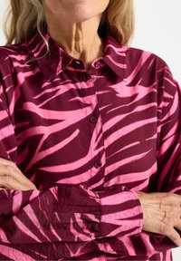 Bordeaux skjorte med knapper, prydet med lyserøde zebra-striber, lange ærmer, krave og samlede manchetter, lavet af let, struktureret stof.