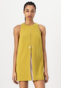 A sleeveless dress in mustard yellow with a fitted bodice, featuring a front slit and gold hardware accents at the neckline. Smooth texture.