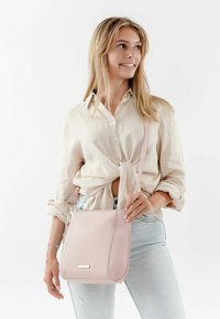 Borsa a mano rosa chiaro realizzata in materiale testurizzato; presenta un accento in hardware color oro. Design semplice con tracolla regolabile.