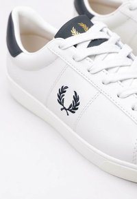 Sneaker in pelle bianca dal design elegante, con un tallone blu navy e un logo di alloro ricamato sul lato. Lacci bianchi.