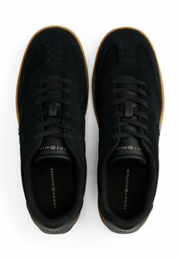 Zapatillas de ante negras con cierre de cordones y detalles perforados, con suela de goma y una sutil marca en el cuello.