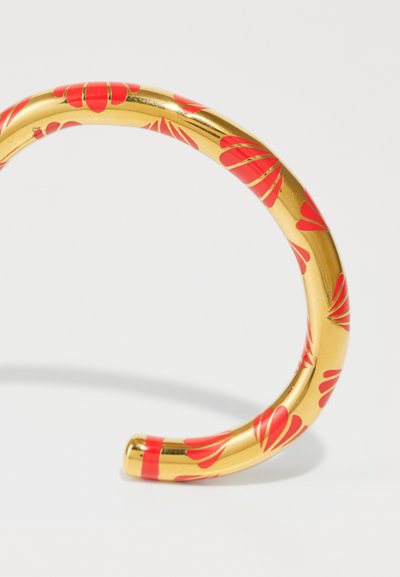 Brazalete de pu�ño dorado con un acabado brillante, decorado con patrones de pétalos rojos. Diseño curvado y suave con bordes redondeados.
