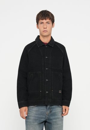 Black denim jacket with a collared neckline, button closure, two front pockets, and contrasting stitching details. Worn over light blue jeans.